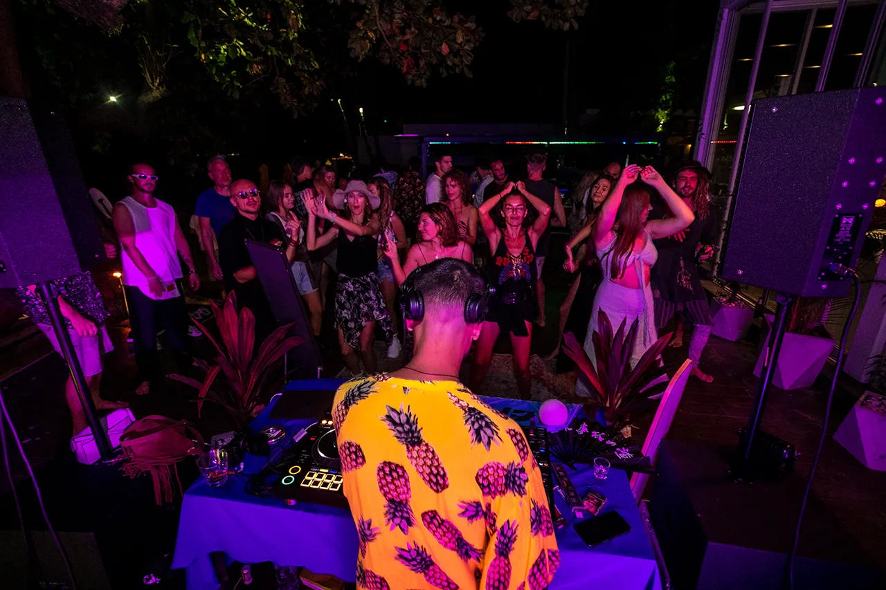 DJ playing lively music during the Full Moon Warm-Up Party at Explorar Koh Phangan, with guests dancing in a vibrant and energetic atmosphere.