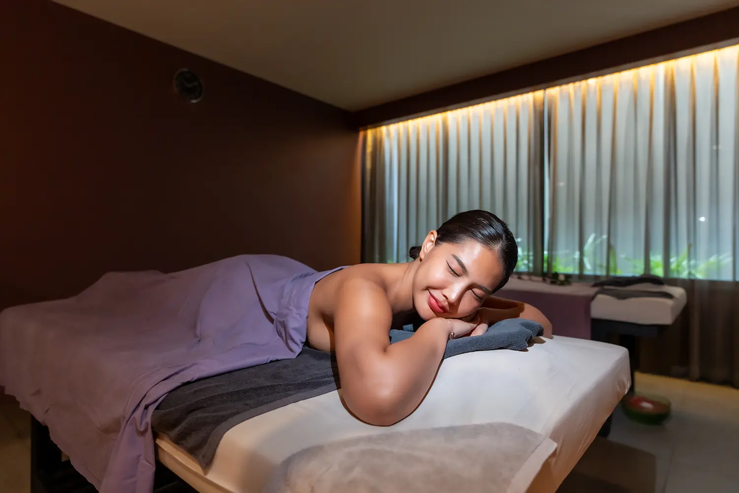 A serene moment of relaxation as a woman receives a rejuvenating massage at Exhale Wellness & Spa, set in the tranquil atmosphere of Explorar Koh Samui.