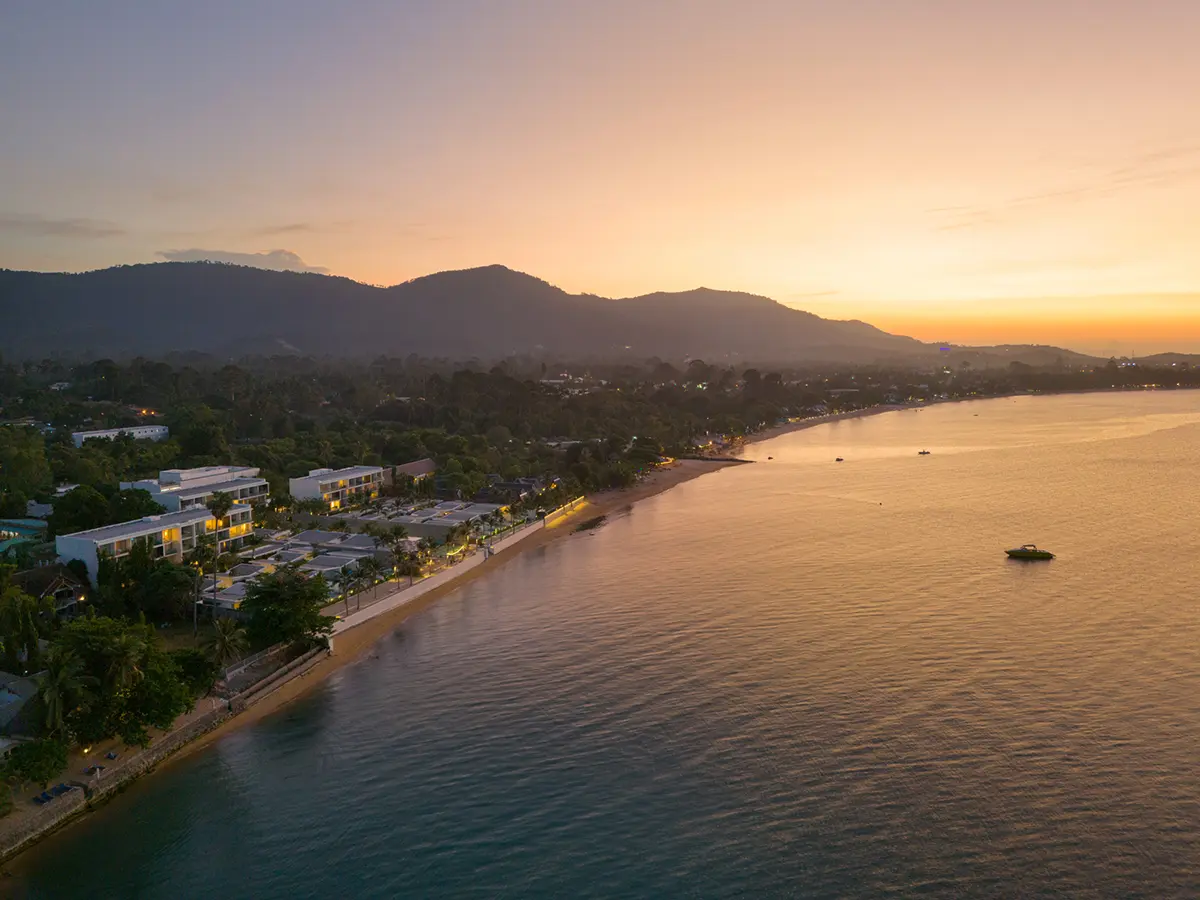 A stunning drone view of Explorar Koh Samui Resort at sunset, with golden skies and turquoise waters.